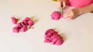 Barn som formar en sköldpadda av rosa cernitlera.